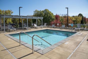 Outdoor pool at 71 France Apartments during the day time. Pool is surrounded by a spacious sundeck with lounge seating and covered pergola.